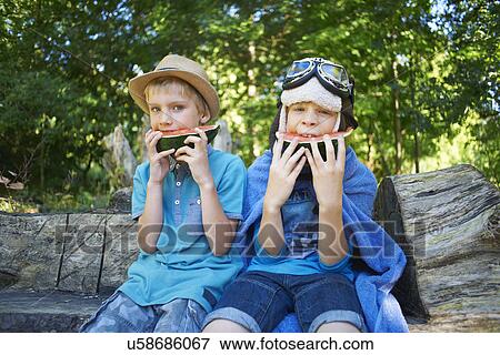 Stock Photo - Two young boys eating watermelon in the park. Fotosearch