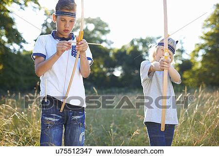 Two young boys holding bow and arrow View Large Photo Image Stock Photo - Two young boys holding bow and arrow. Fotosearch