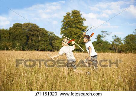 Two young boys running with bow and arrow View Large Photo Image Stock Image - Two young boys running with bow and arrow. Fotosearch