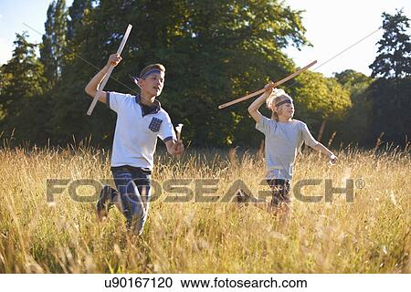 Stock Image - Two young boys running with bow and arrow. Fotosearch