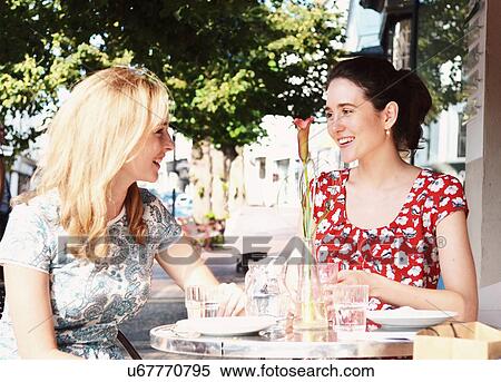 Two young women chatting at sidewalk cafe View Large Photo Image Stock Photography - Two young women chatting at sidewalk cafe. Fotosearch