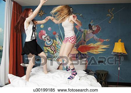 Two young women dancing on hotel bed View Large Photo Image Stock Photography - Two young women dancing on hotel bed. Fotosearch