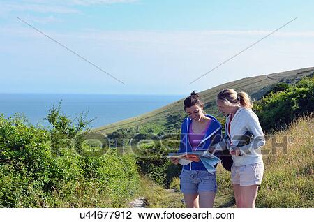 Stock Image - Two young women on coastal path with map. Fotosearch