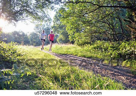 Two young women runners running along forest track in morning View Large Photo Image Stock Photo - Two young women runners running along forest track in morning. Fotosearch