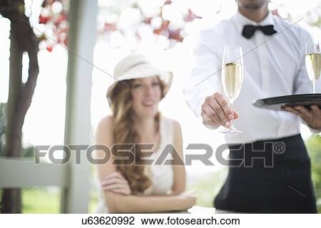 Waiter serving champagne in garden restaurant View Large Photo Image Stock Image - Waiter serving champagne in garden restaurant. Fotosearch