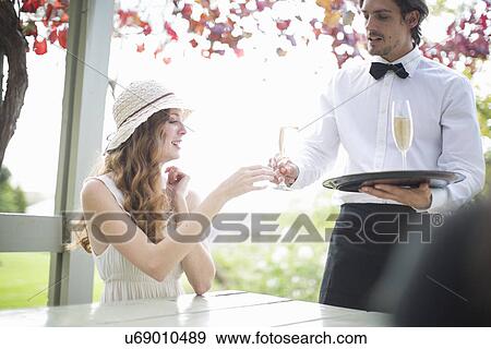 Waiter serving champagne to young woman in garden restaurant View Large Photo Image Stock Photo - Waiter serving champagne to young woman in garden restaurant. Fotosearch