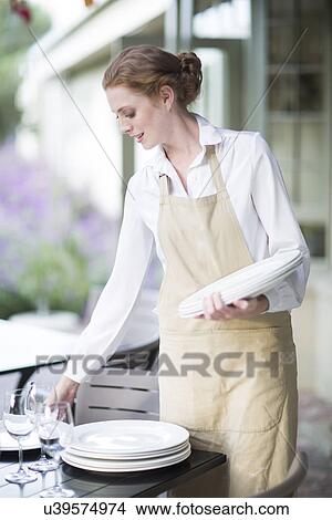 Waitress organizing plates on table in patio restaurant View Large Photo Image Picture - Waitress organizing plates on table in patio restaurant. Fotosearch