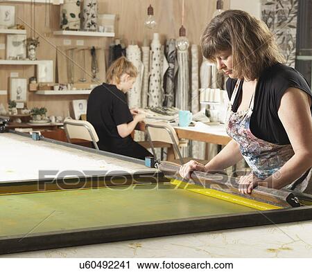 Stock Image - Woman hand-printing textile in workshop. Fotosearch