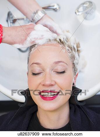 Stock Photo - Woman having hair shampooed in salon. Fotosearch