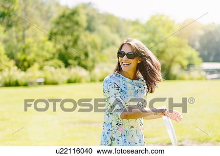 Stock Image - Woman playing disc game in the park. Fotosearch