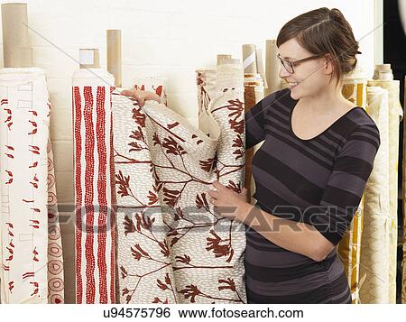 Stock Photograph - Woman showing off fabric in hand-printed textile workshop. Fotosearch