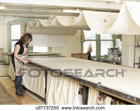 Stock Image - Woman working by drying system in hand-printing textile workshop. Fotosearch