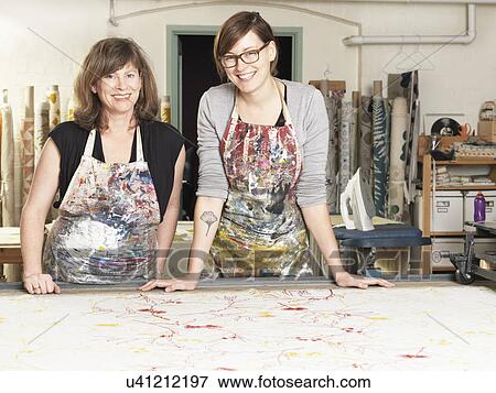 Stock Photo - Women at work table in hand-printing textile workshop. Fotosearch