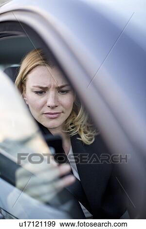 Stock Photo - Worried businesswoman reading texts on smartphone in city traffic jam. Fotosearch