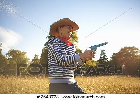 Young boy dressed as cowboy, holding toy gun View Large Photo Image Stock Photo - Young boy dressed as cowboy, holding toy gun. Fotosearch