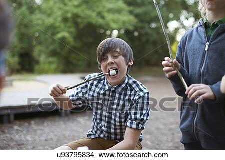 Young boy eating toasted marshmallow from stick View Large Photo Image Picture - Young boy eating toasted marshmallow from stick. Fotosearch