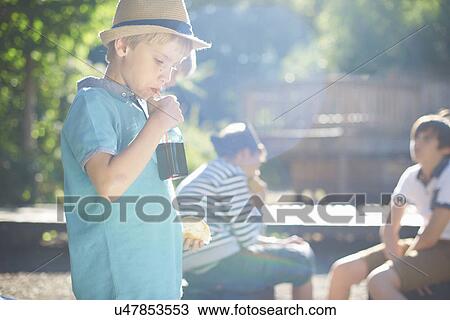 Stock Image - Young boy having lunch in park. Fotosearch