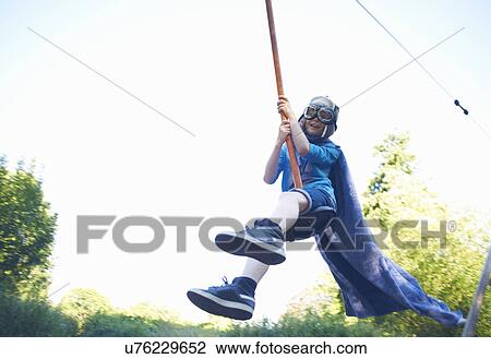 Stock Image - Young boy in fancy dress, on zip wire. Fotosearch