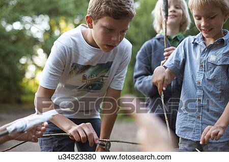 Young boys cooking fish over barbecue View Large Photo Image Stock Image - Young boys cooking fish over barbecue. Fotosearch