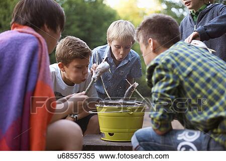 Stock Photography - Young boys cooking fish over barbecue. Fotosearch