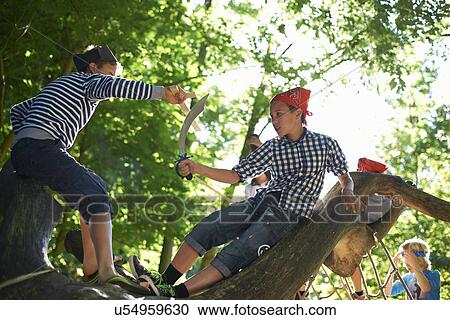 Stock Image - Young boys dressed as pirates, playing in tree. Fotosearch