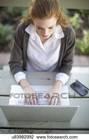 Young businesswoman typing on laptop at garden table View Large Photo Image Stock Image - Young businesswoman typing on laptop at garden table. Fotosearch