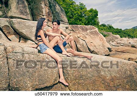 Young couple sitting together on rocks View Large Photo Image Stock Photo - Young couple sitting together on rocks. Fotosearch
