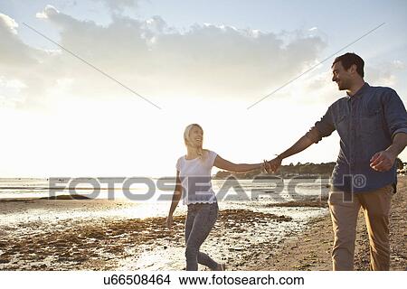 Picture - Young couple walking on beach. Fotosearch