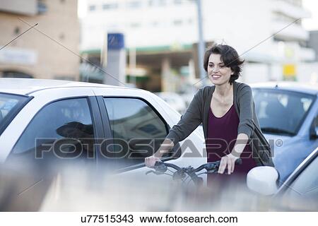Young female cyclist commuting through city traffic jam View Large Photo Image Stock Image - Young female cyclist commuting through city traffic jam. Fotosearch