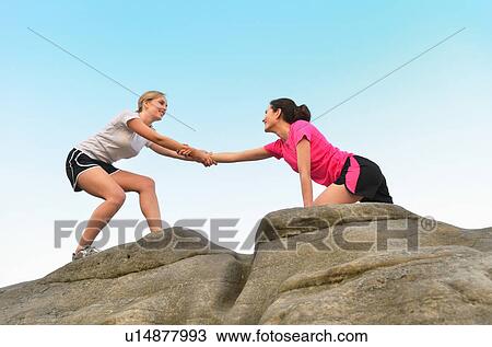 Young female runner helping friend to top of rock formation View Large Photo Image Stock Image - Young female runner helping friend to top of rock formation. Fotosearch