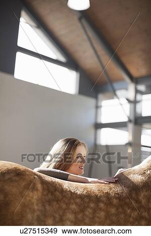 Stock Photo - Young female stablehand petting the back of dappled horse. Fotosearch