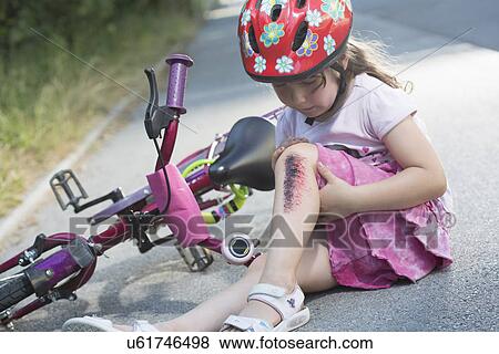 Young girl with injured leg sitting on road with bicycle View Large Photo Image Stock Photo - Young girl with injured leg sitting on road with bicycle. Fotosearch