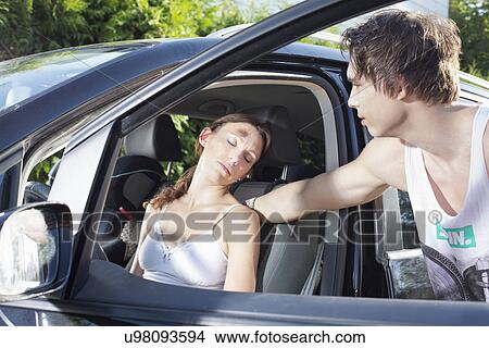 Picture - Young man checking on injured female driver. Fotosearch