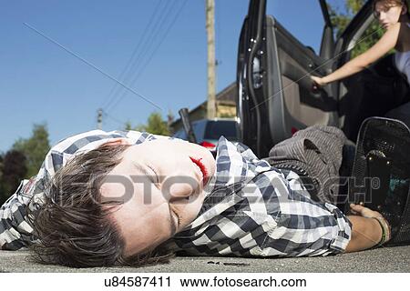 Stock Image - Young man hit by car lying on road. Fotosearch