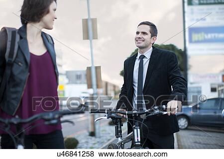 Stock Photo - Young woman chatting to businessman whilst cycling to work. Fotosearch