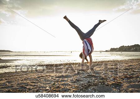Picture - Young woman doing handstand on Bournemouth beach, Dorset, UK. Fotosearch