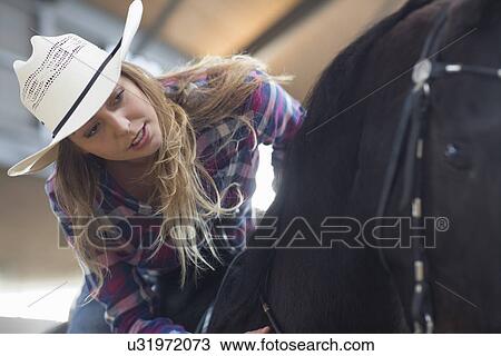 Young woman horseback rider in indoor paddock View Large Photo Image Stock Image - Young woman horseback rider in indoor paddock. Fotosearch