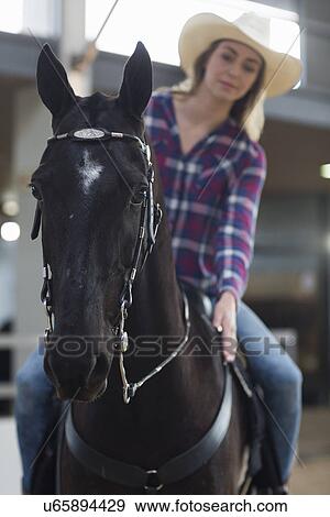 Young woman horseback rider patting horse in indoor paddock View Large Photo Image Stock Photo - Young woman horseback rider patting horse in indoor paddock. Fotosearch