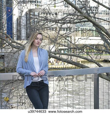Young woman leaning against railings at city riverside View Large Photo Image Stock Image - Young woman leaning against railings at city riverside. Fotosearch