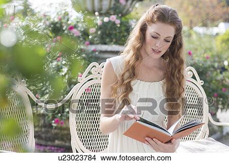 Picture - Young woman looking at a book. Fotosearch