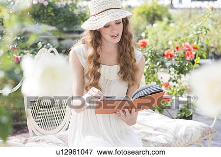 Young woman looking at a book View Large Photo Image Stock Photo - Young woman looking at a book. Fotosearch