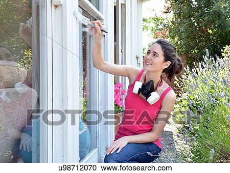 Young woman sitting painting house window View Large Photo Image Stock Image - Young woman sitting painting house window. Fotosearch