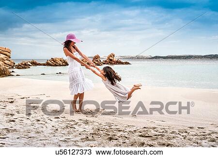 Young woman swinging daughter on beach, La Maddalena, Sardinia, Italy View Large Photo Image Stock Image - Young woman swinging daughter on beach, La Maddalena, Sardinia, Italy. Fotosearch