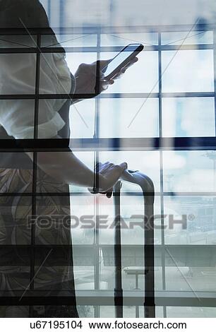 Young woman using smartphone and holding handle of suitcase, mid section View Large Photo Image Picture - Young woman using smartphone and holding handle of suitcase, mid section. Fotosearch