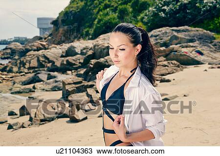 Stock Image - Young woman, wearing swimwear, on beach. Fotosearch