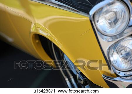 Stock Image - Front fender and headlight of yellow car. Fotosearch