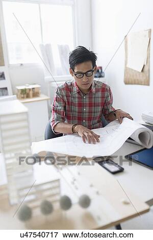 Architect looking at blueprints in office View Large Photo Image Stock Photo - Architect looking at blueprints in office. Fotosearch