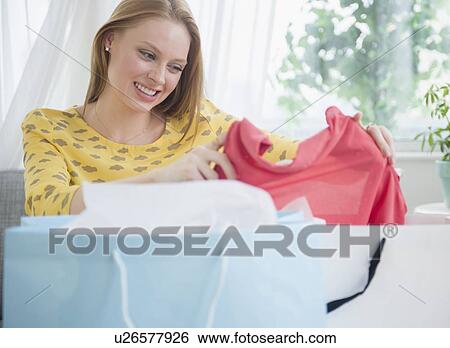 Stock Photograph - Blond woman looking at new clothing. Fotosearch