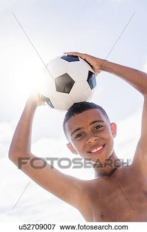 Boy (10-11) holding soccer ball on head View Large Photo Image Stock Photo - Boy (10-11) holding soccer ball on head. Fotosearch