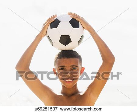 Stock Photo - Boy (10-11) holding soccer ball on head. Fotosearch